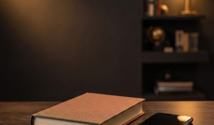 Guide relié posé à côté d'un smartphone sur un bureau en bois